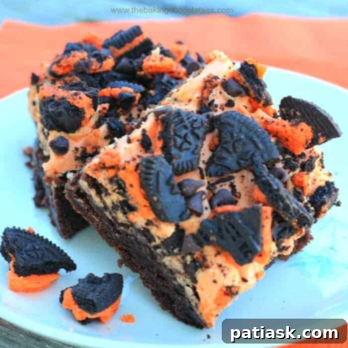 Decadent Orange ButterScream Oreo Brownies 2 Two orange buttercream iced brownies topped with Halloween Oreos, showcasing the vibrant orange and dark chocolate contrast.