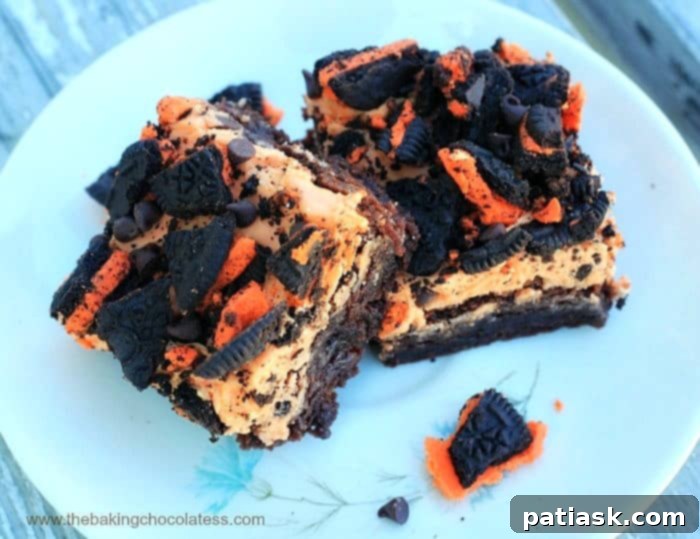 Decadent Orange ButterScream Oreo Brownies 3 A close-up of orange buttercream brownies on a white plate, adorned with Halloween Oreos and chocolate chips.
