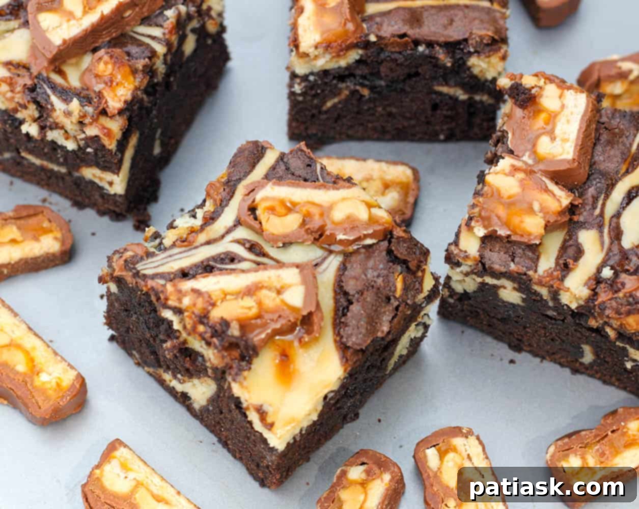 Rich Kahlua Cheesecake Snickers Brownies recipe featuring candy bar pieces and a luscious cream cheese swirl baked in
