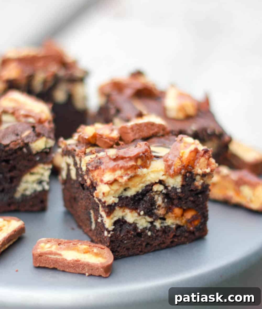 Close-up of baked Kahlua Cheesecake Snickers Brownies, showing the perfect swirl and candy bar pieces