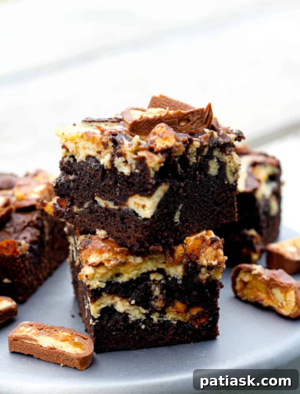 A large tray of Kahlua Cheesecake Snickers Brownies, perfectly baked with a creamy swirl and candy bar chunks, ready to be cut and served.