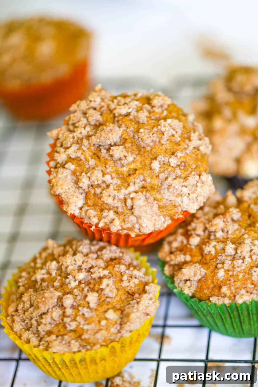 Spiced Pumpkin Crumble Muffins 6 Two freshly baked pumpkin streusel muffins, showcasing the generous amount of golden-brown crumb topping.