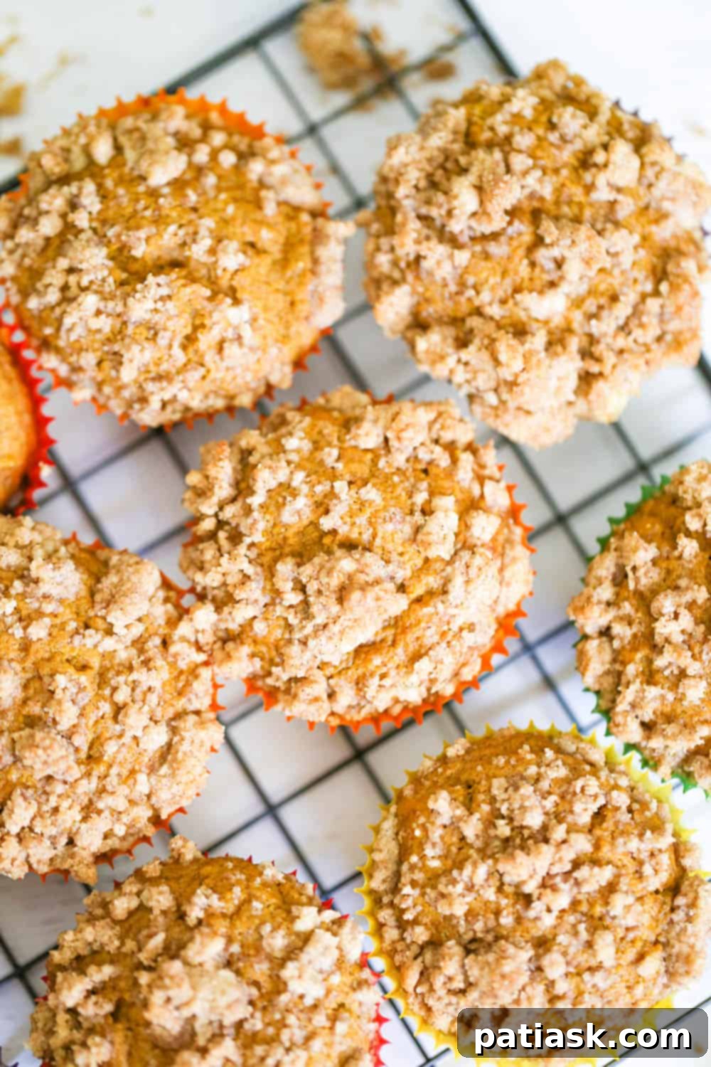 Spiced Pumpkin Crumble Muffins 3 A close-up view of freshly baked pumpkin streusel muffins on a cooling rack, highlighting the irresistible streusel topping.