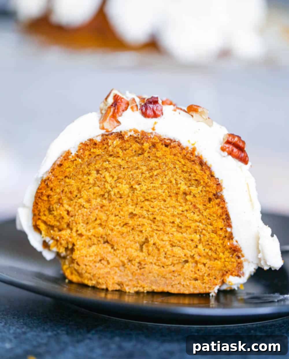 A delectable slice of Pumpkin Bundt Cake showing its moist interior and thick cream cheese frosting