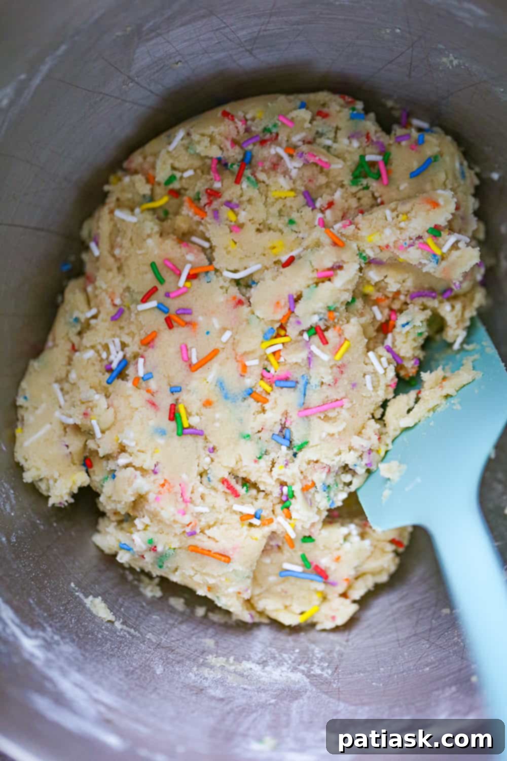 A freshly baked sprinkle sugar cookie with a bite taken out, revealing its soft interior