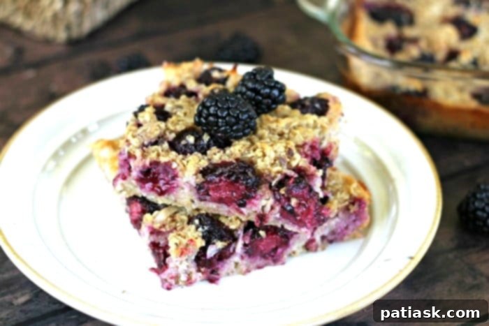 Tropical Blackberry Coconut Baked Oats 5 A slice of baked blackberry coconut oatmeal, showing layers of oats and berries, ready to be enjoyed.