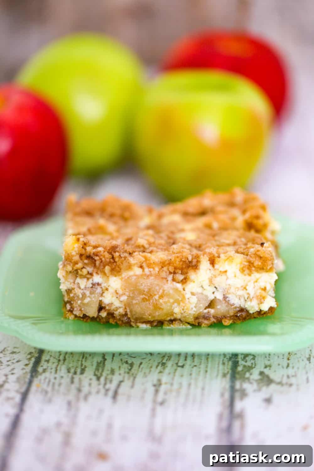 Autumn Apple Crumble Cheesecake Squares 8 A single slice of apple cheesecake bar on a white plate