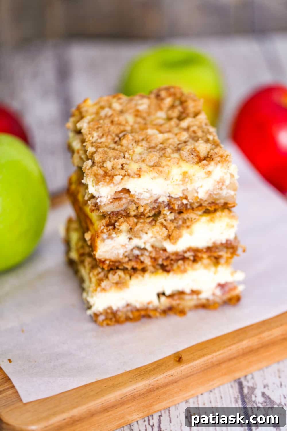 Autumn Apple Crumble Cheesecake Squares 5 Close-up of baked apple crisp cream cheese bars with a dollop of whipped cream and caramel drizzle