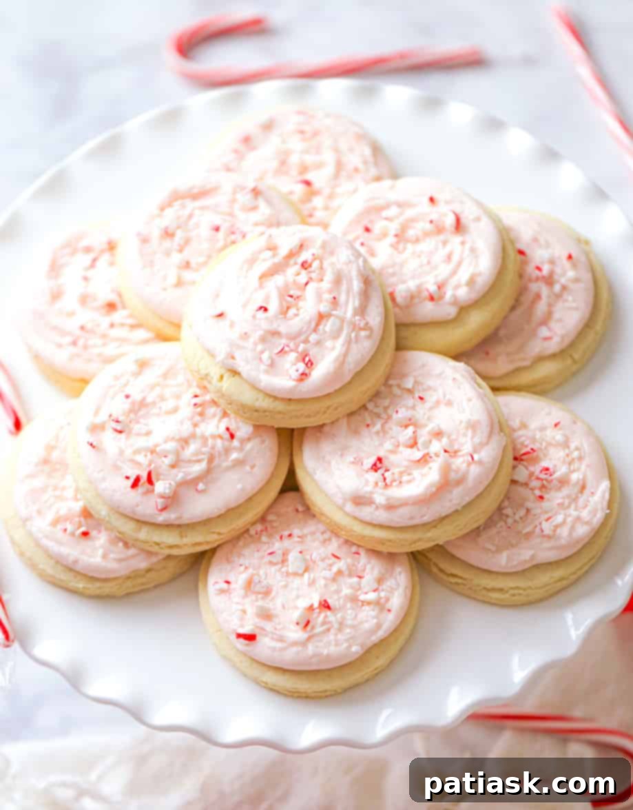 Peppermint Swirl Cookies 2 Candy Cane Frosted Cookies, garnished with crushed peppermint candies, sitting on a festive plate.