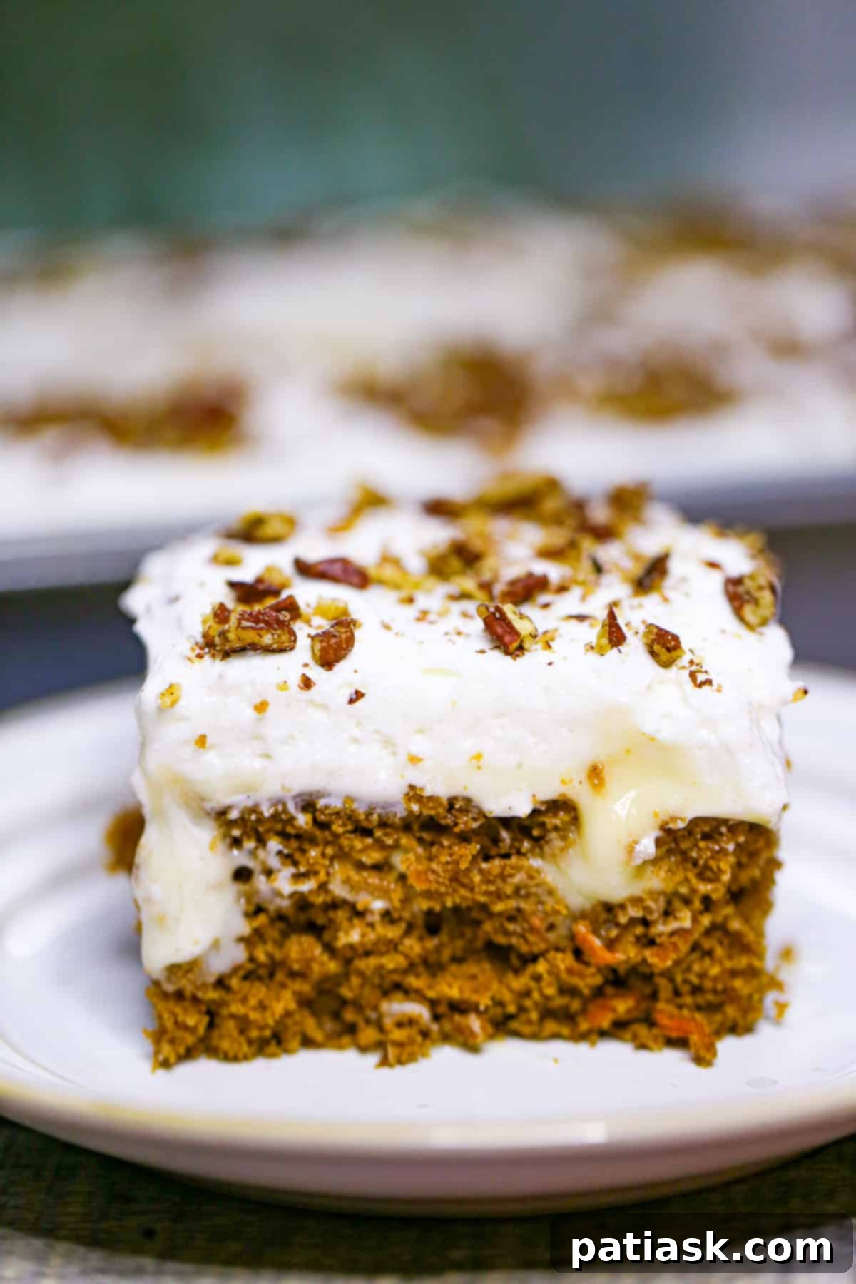 Carrot Cake Delight with Creamy Pockets 2 Carrot Cake Poke Cake sliced, showing layers of cake, pudding, and whipped cream