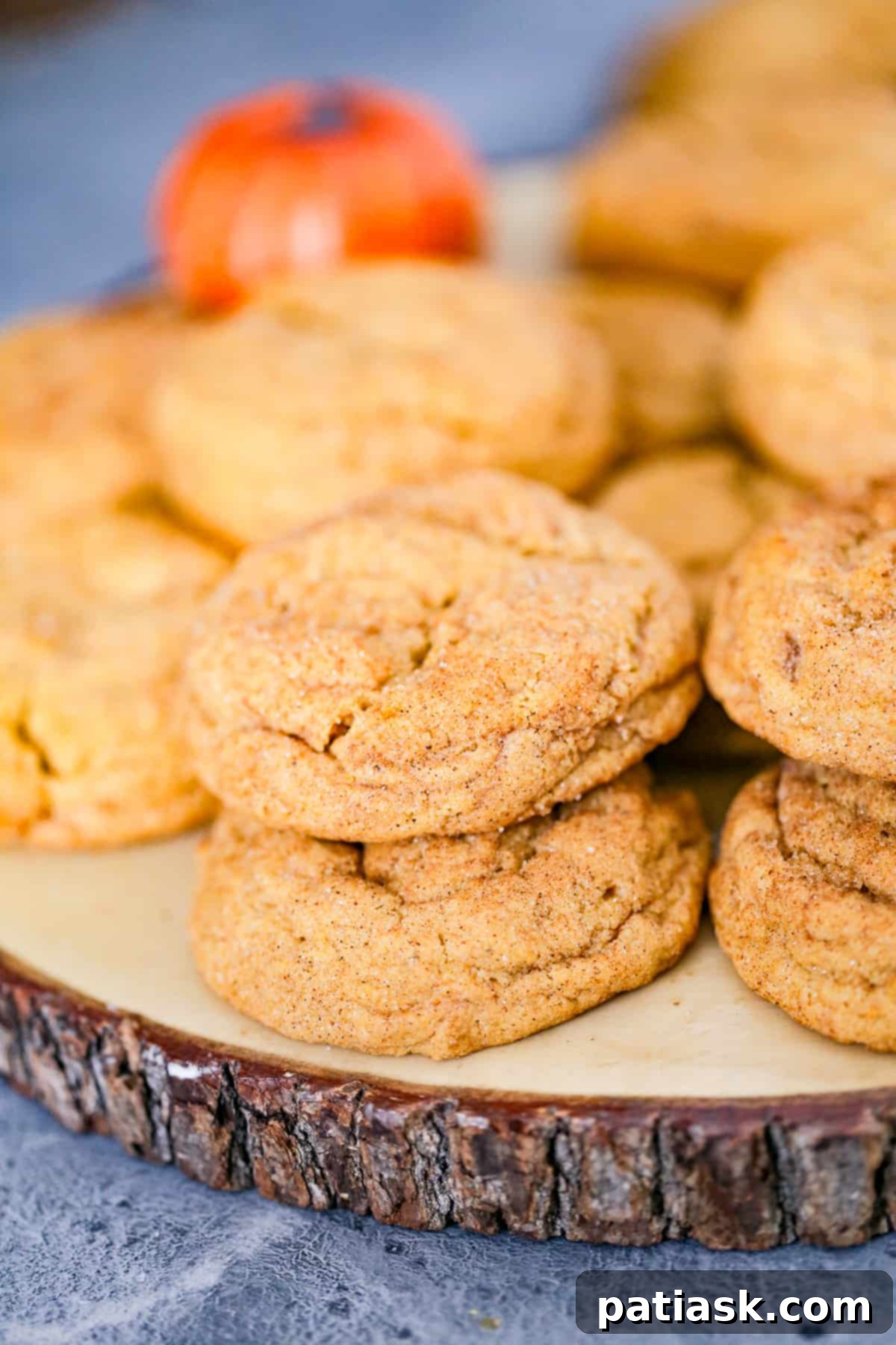 A stack of delicious pumpkin snickerdoodle cookies with fall leaves in the background