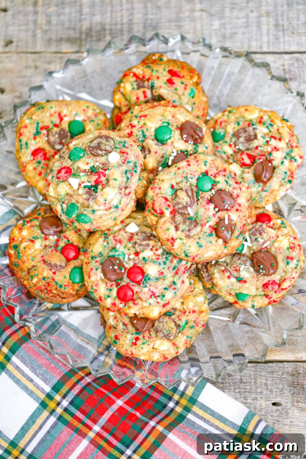 A bowl of red and green M&M's and sprinkles next to cookie dough