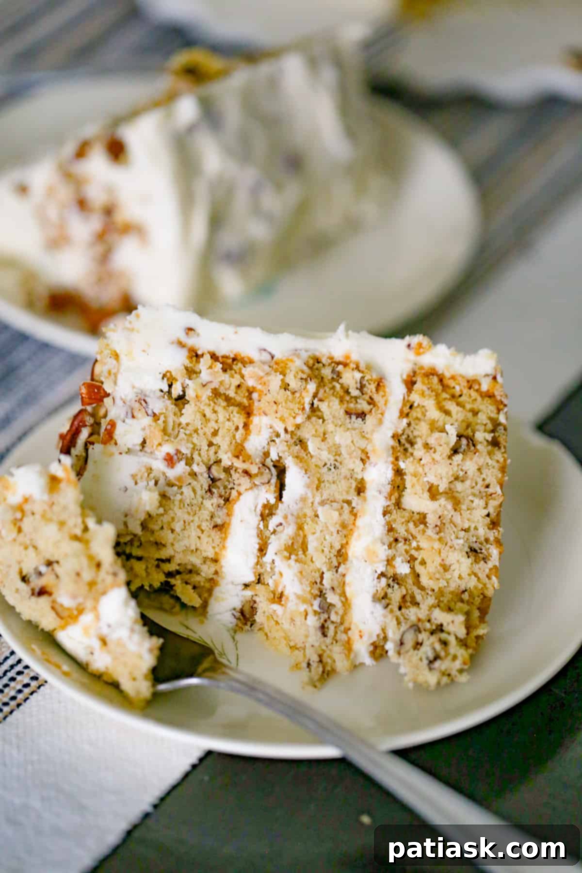 Close-up of a slice of Italian Cream Cake revealing layers of moist cake, coconut, pecans, and cream cheese frosting.