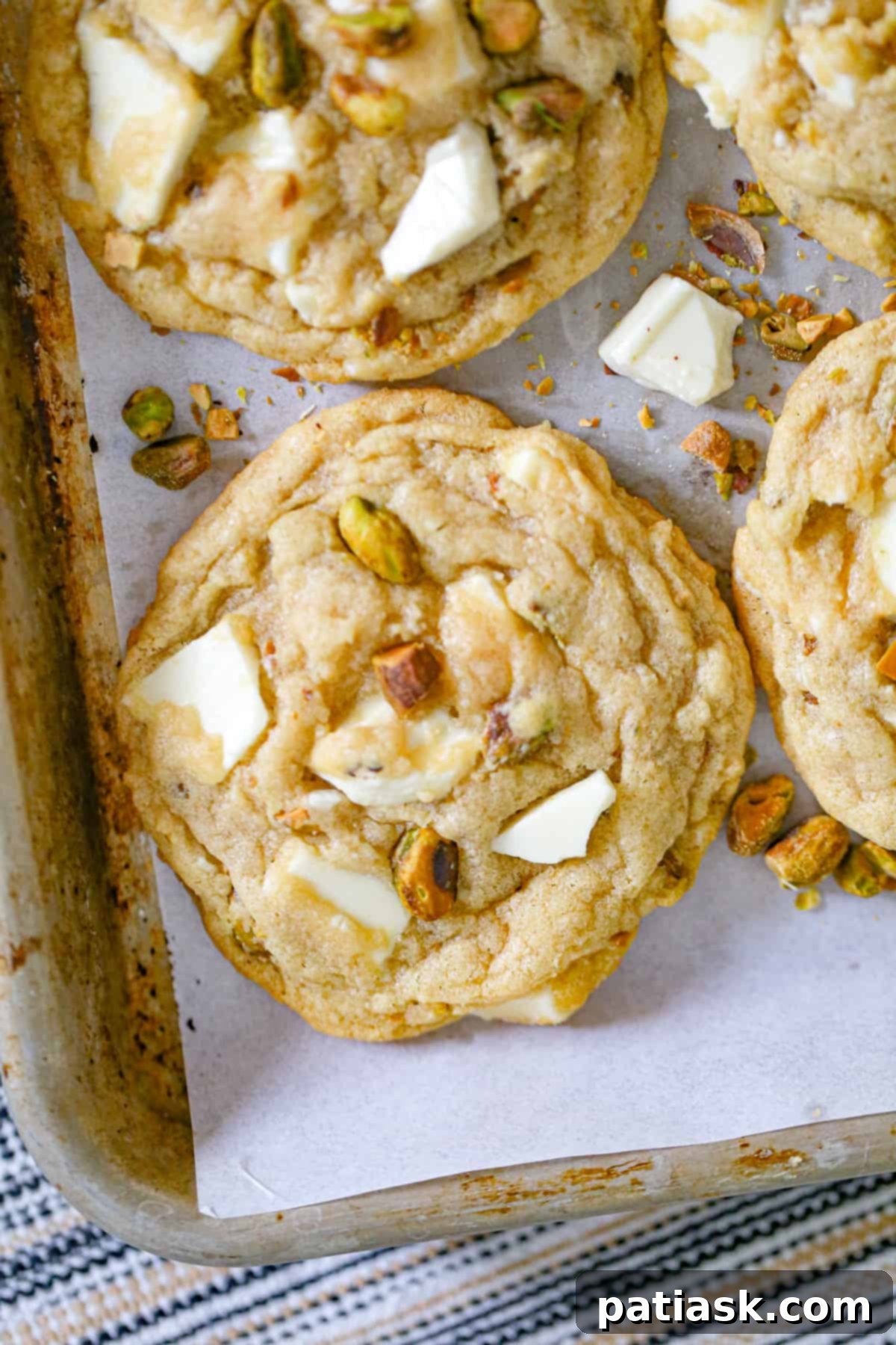 White chocolate pistachio cookies cooling on a wire rack, with some in the background