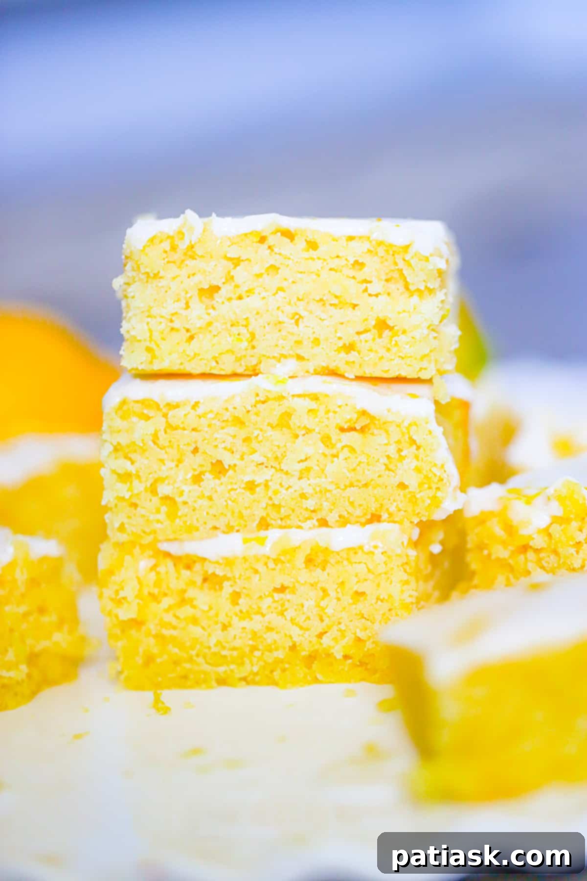 A selection of homemade lemon brownies on a rustic wooden board, garnished with lemon slices and mint leaves.