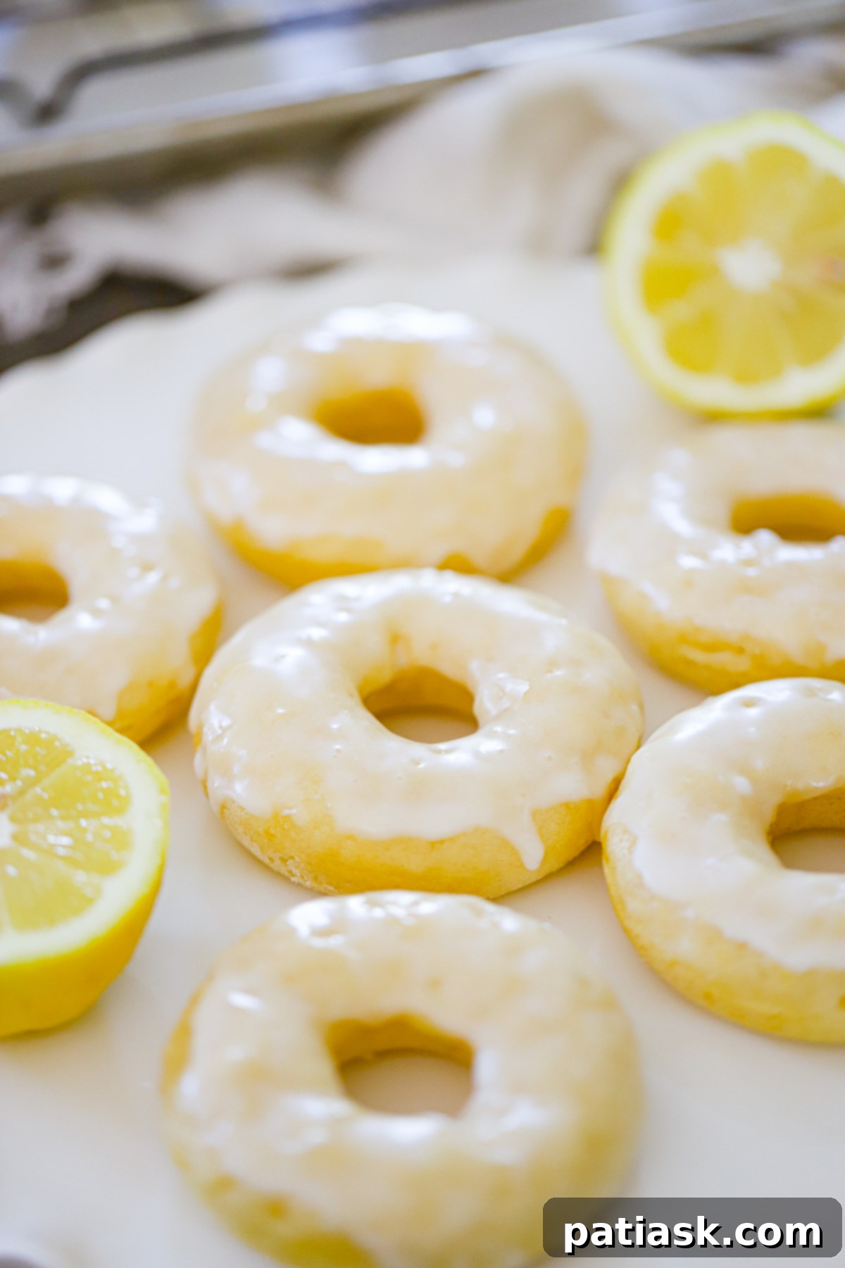 Lemon Zing Donuts 2 Delicious homemade lemon glazed donuts on a white platter, sprinkled with fresh lemon zest, ready to be enjoyed.