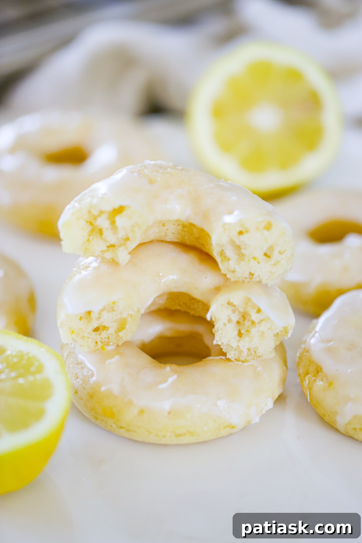 Lemon Zing Donuts 6 A close-up of a single perfectly baked and glazed lemon donut, showcasing its fluffy texture and vibrant yellow glaze.