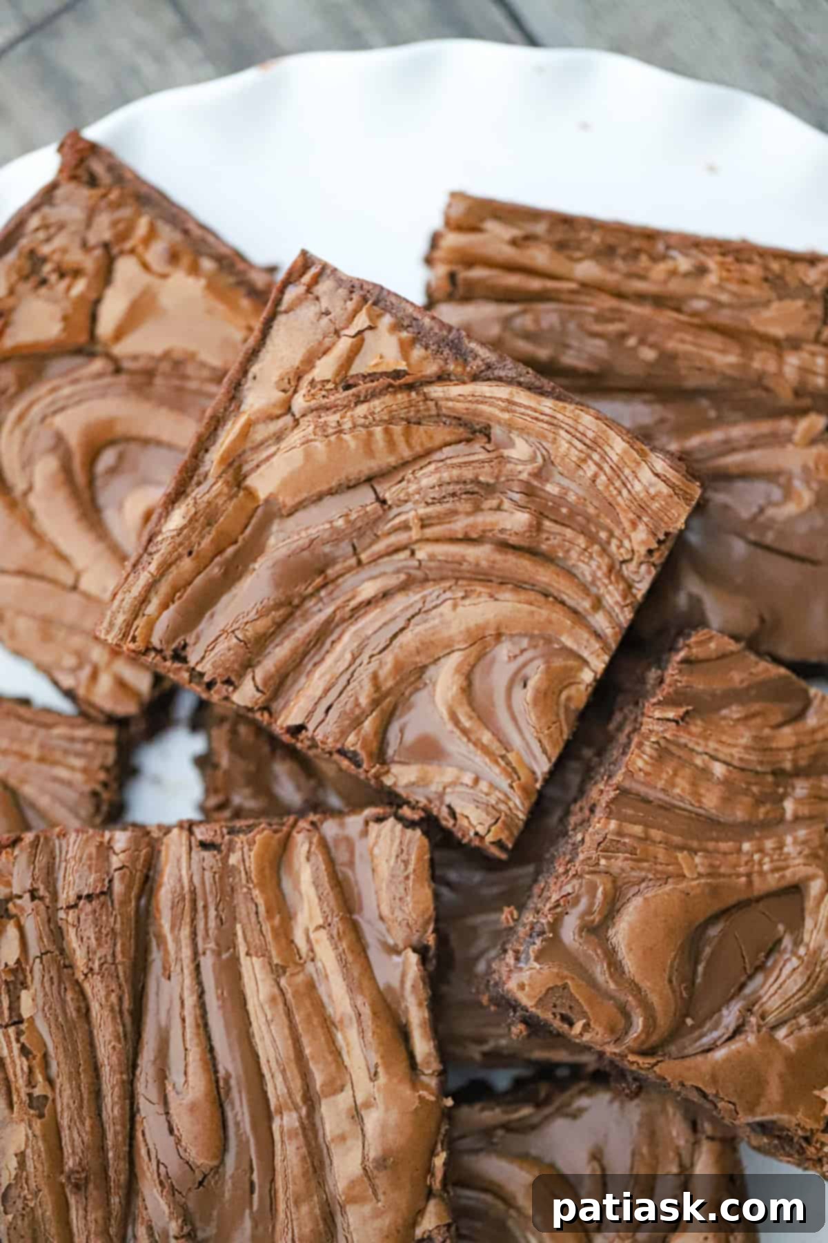 Decadent Nutella Swirl Brownies 2 Swirled chocolate hazelnut brownies fresh from the oven, showcasing a beautiful crackle top and gooey interior.