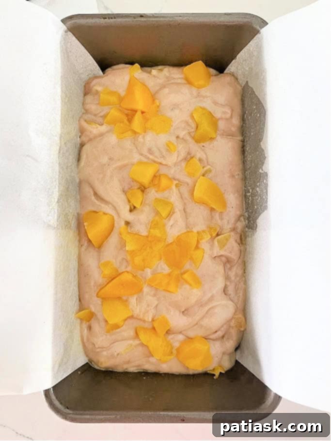 Easy Peach Cobbler Quick Bread 6 Peach cobbler bread batter evenly spread in a parchment-lined loaf pan, ready for baking, an essential step for homemade peach bread.