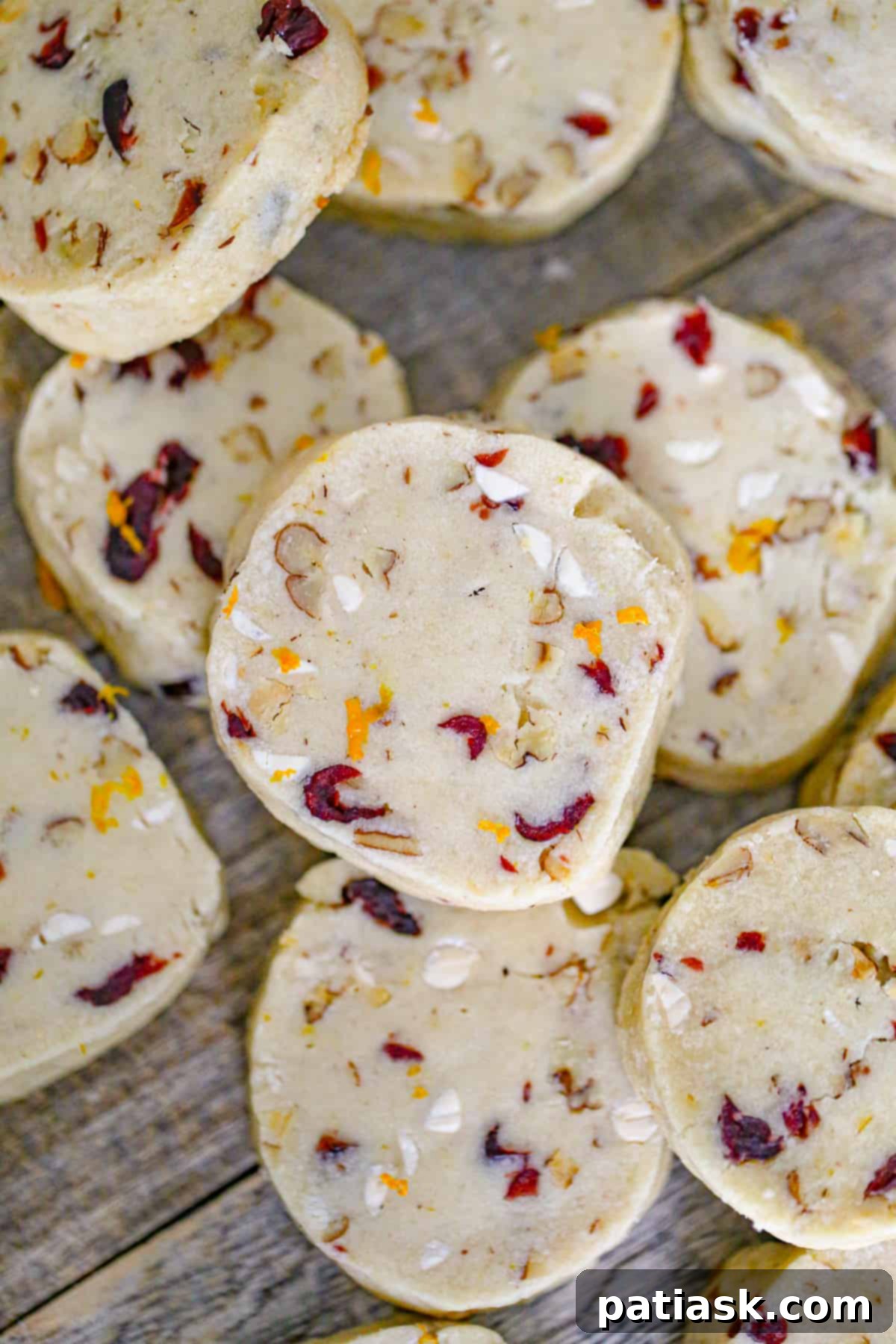 A festive pile of cranberry orange chocolate chip shortbread cookies on a white plate, ready for holiday enjoyment.