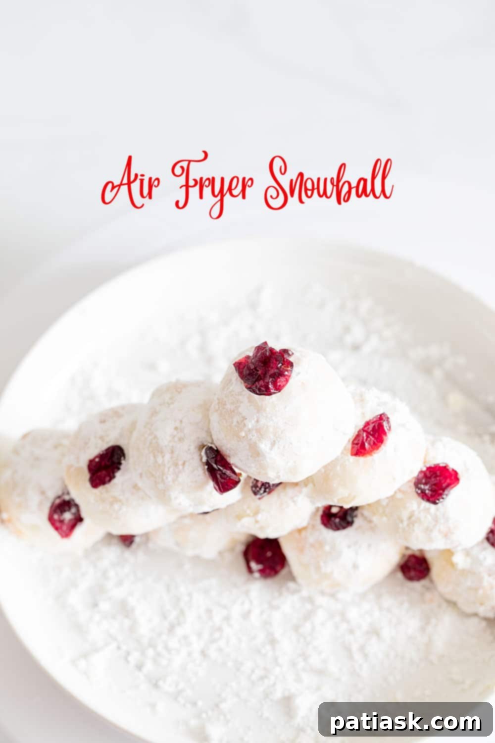 Pistachio and cranberry snowball cookies, dusted with powdered sugar, arranged on a plate.