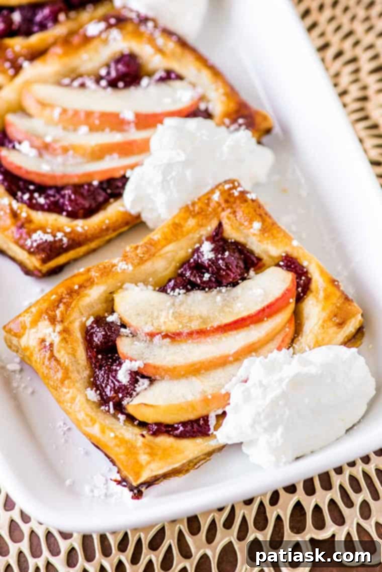Golden brown cranberry apple puff pastry tarts, arranged on a serving plate.