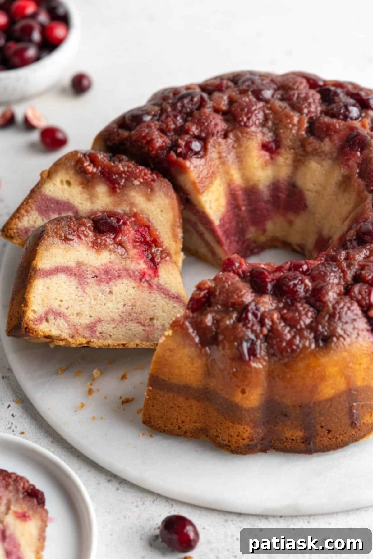 A festive cranberry bundt cake, dusted with powdered sugar and garnished with fresh berries.