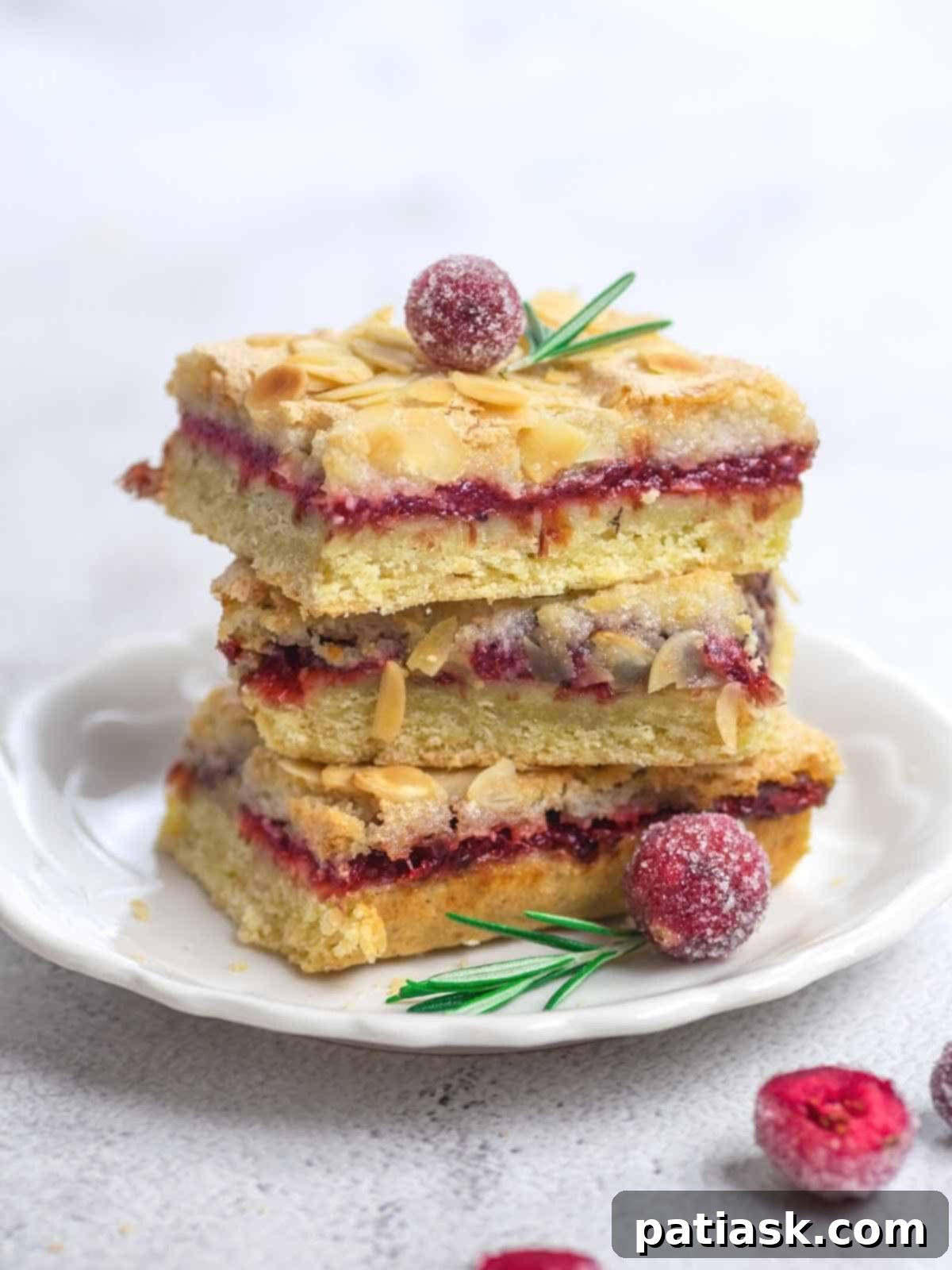 Close-up of a slice of cranberry lemon bar, showing the distinct triple layers of lemon base, cranberry filling, and meringue topping.