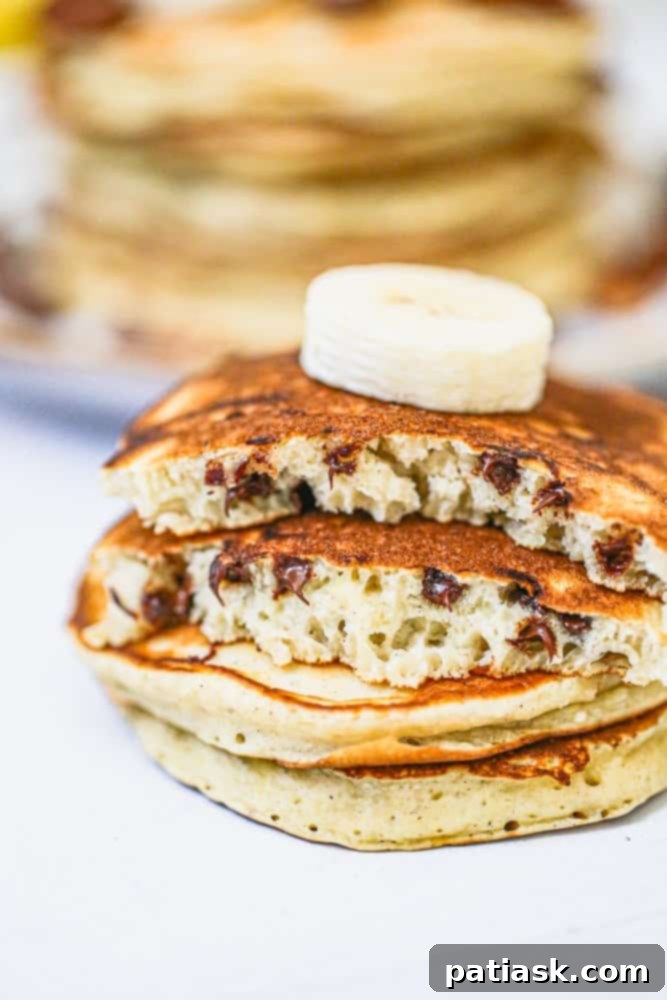 A close-up of golden-brown fluffy pancakes with melted chocolate chips, ready to be served, highlighting their inviting texture and deliciousness.