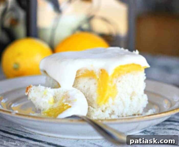 A slice of Lemon Burst Poke Cake showcasing its layers of cake, lemon filling, and whipped cream