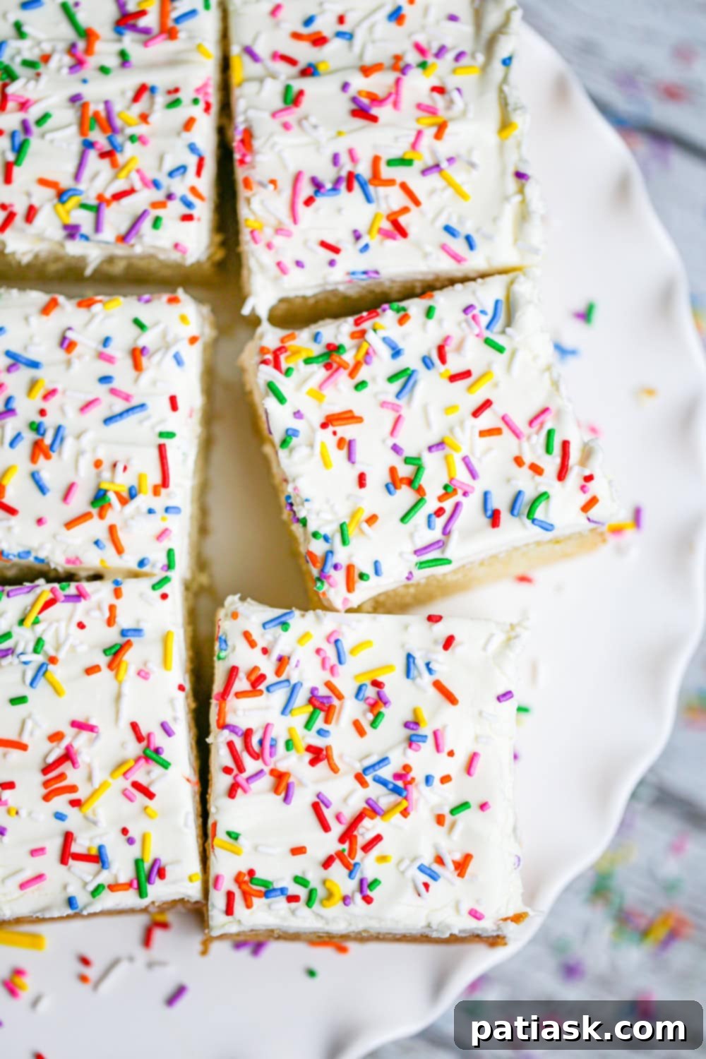 Zesty Lemon Cake 5 Overhead shot of a full lemon snack cake in a square pan, beautifully frosted and decorated with sprinkles.