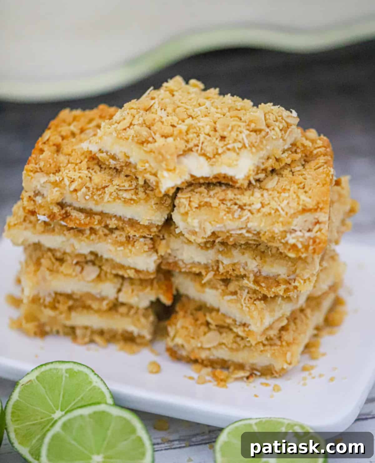 Tropical Zest Oat Crumble Bars 6 Lime Coconut Oatmeal Crumble Bars stacked with a bowl of lime and coconut