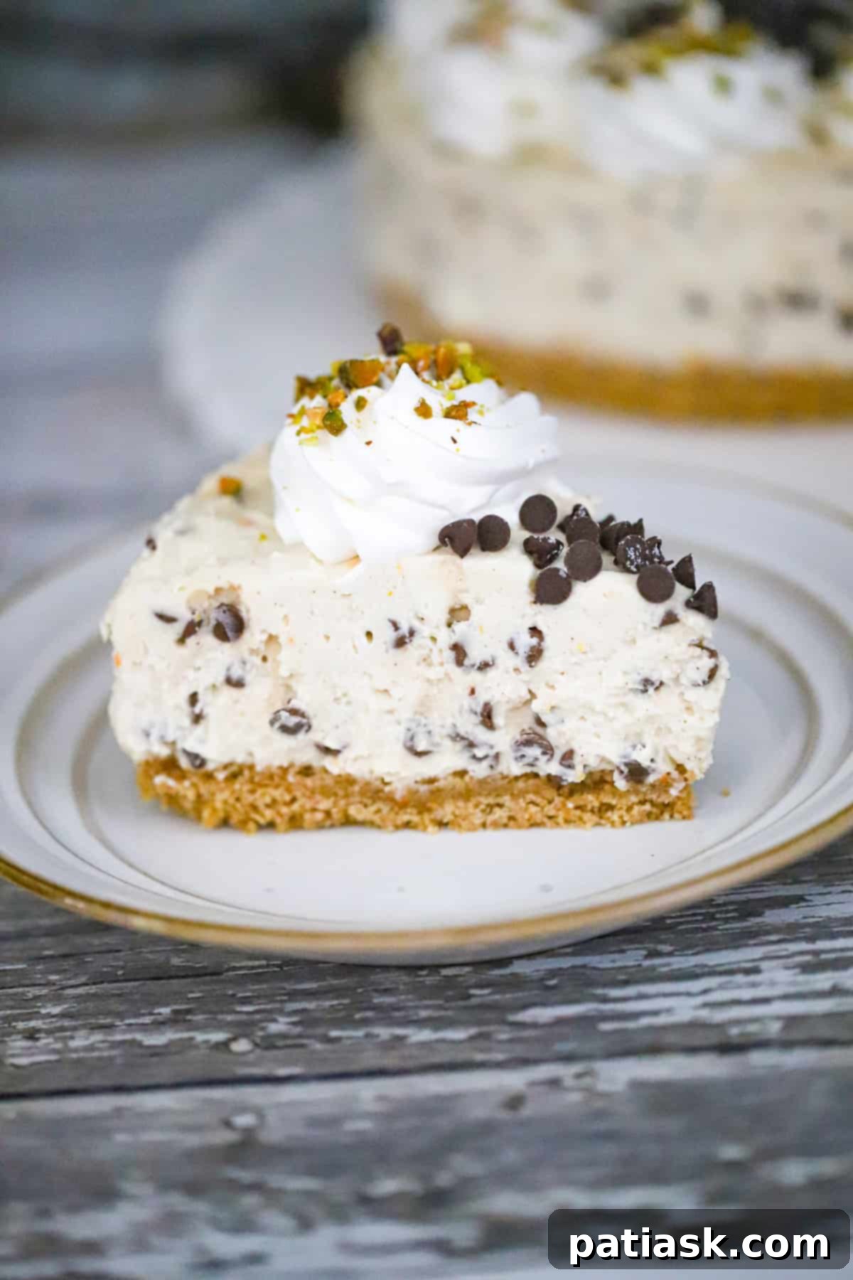 No-Bake Cannoli Cheesecake, a creamy sliceable dessert with a graham cracker crust, ricotta and cream cheese filling, pistachios, and chocolate chips.
