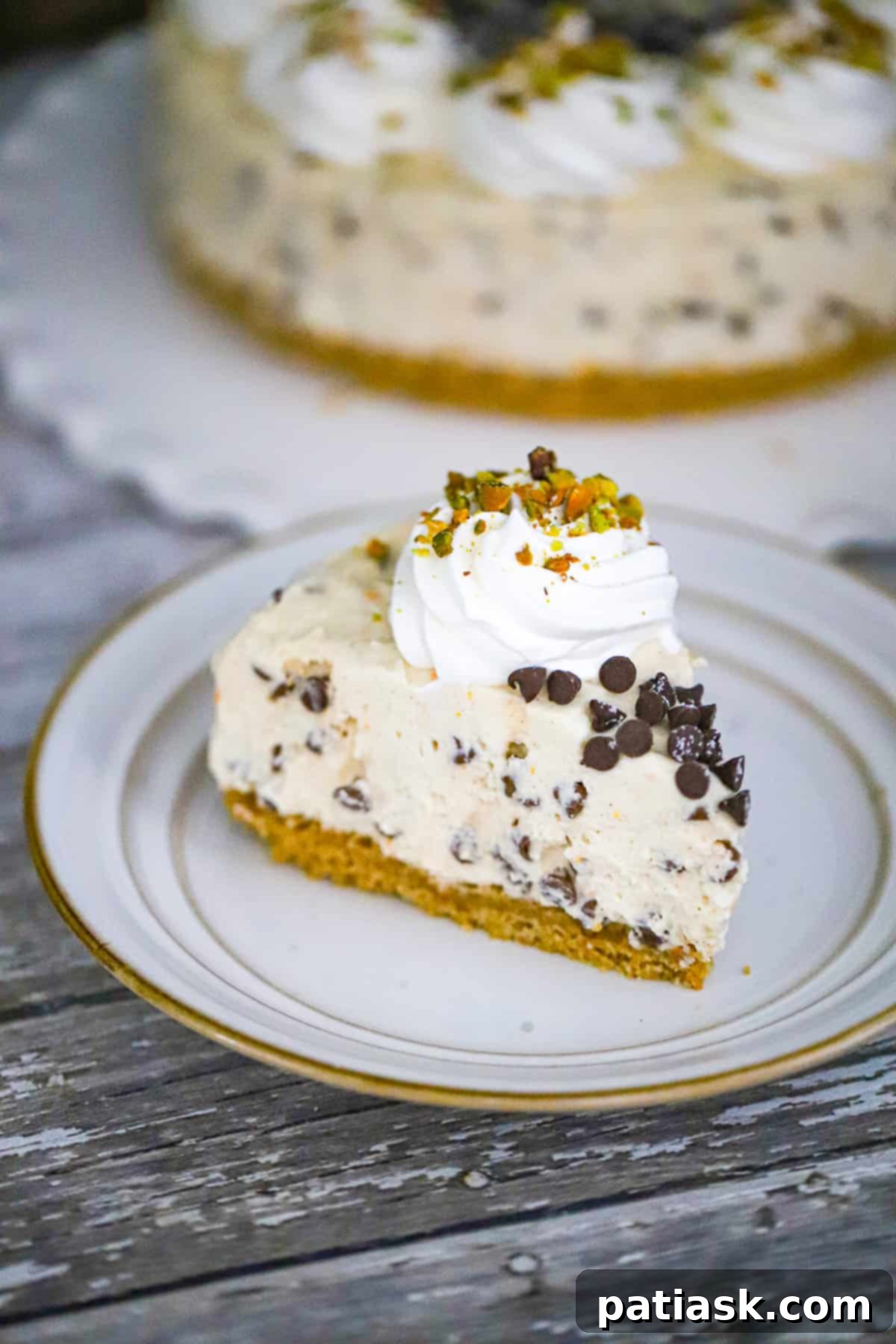 A whole No-Bake Cannoli Cheesecake topped with chocolate chips and pistachios.