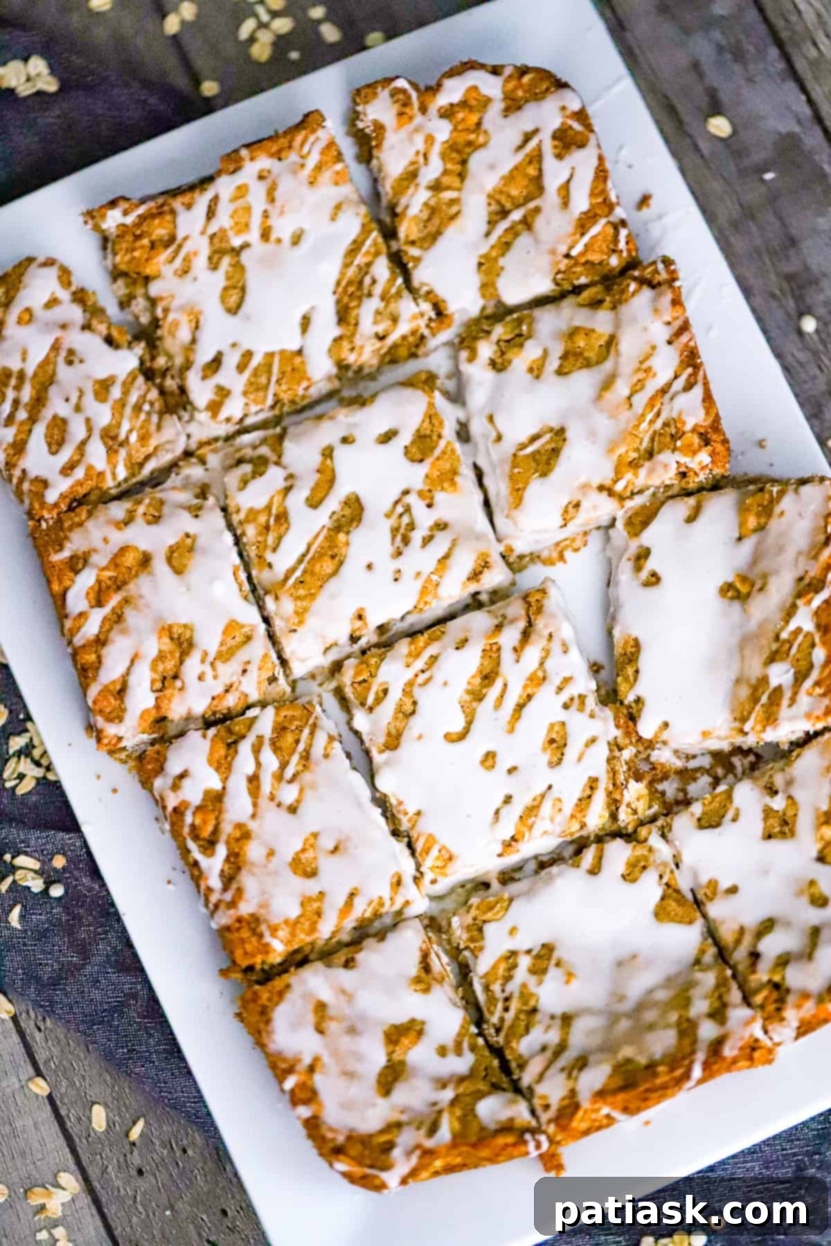 Frosted Oatmeal Bliss Bars 6 A stack of freshly baked, chewy iced oatmeal bars, showing the textured oats and delicious vanilla glaze.