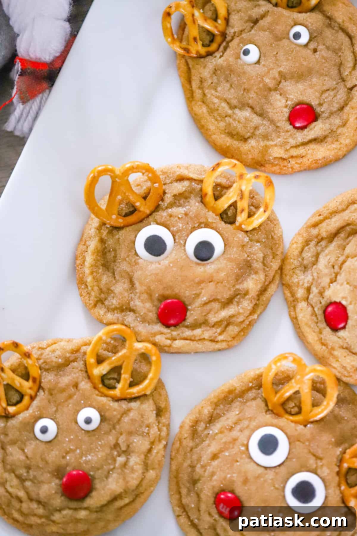 Festive Reindeer Delights 2 Beautifully decorated Christmas Reindeer Cookies with red M&M noses and pretzel antlers.