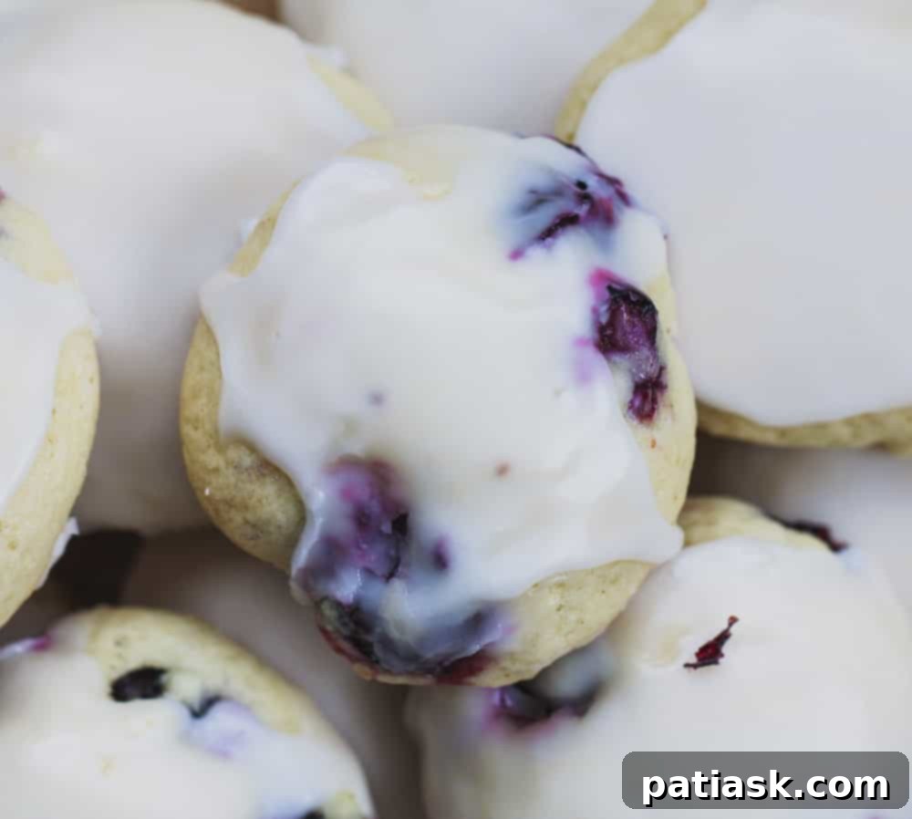 Stack of Soft Lemon & Blueberry Explosion Cookies with fresh lemons