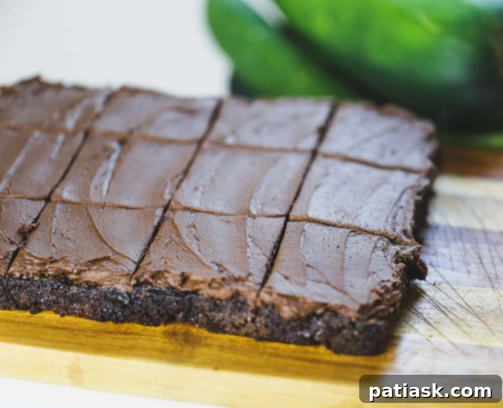 Stacked fudgy cocoa zucchini brownies on a cooling rack