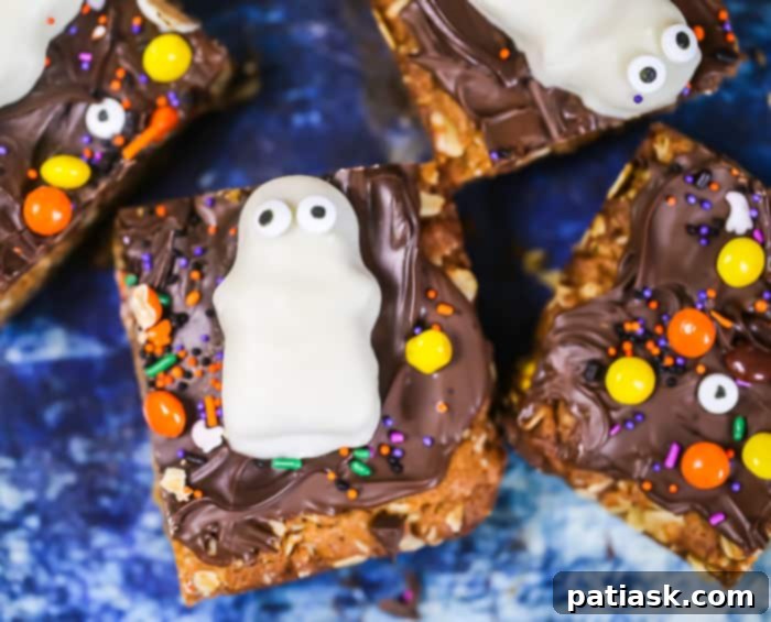 Spooktacular Reeses Monster Cookie Bars 4 Close-up of Flourless Halloween Reese's Monster Cookie Bars, showing the texture of the oatmeal base and the melted chocolate topping with Reese's Pieces.