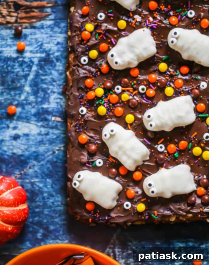 Spooktacular Reeses Monster Cookie Bars 5 Overhead view of a tray of Flourless Halloween Reese's Monster Cookie Bars, freshly decorated with Reese's Ghosts, eyeballs, and sprinkles.