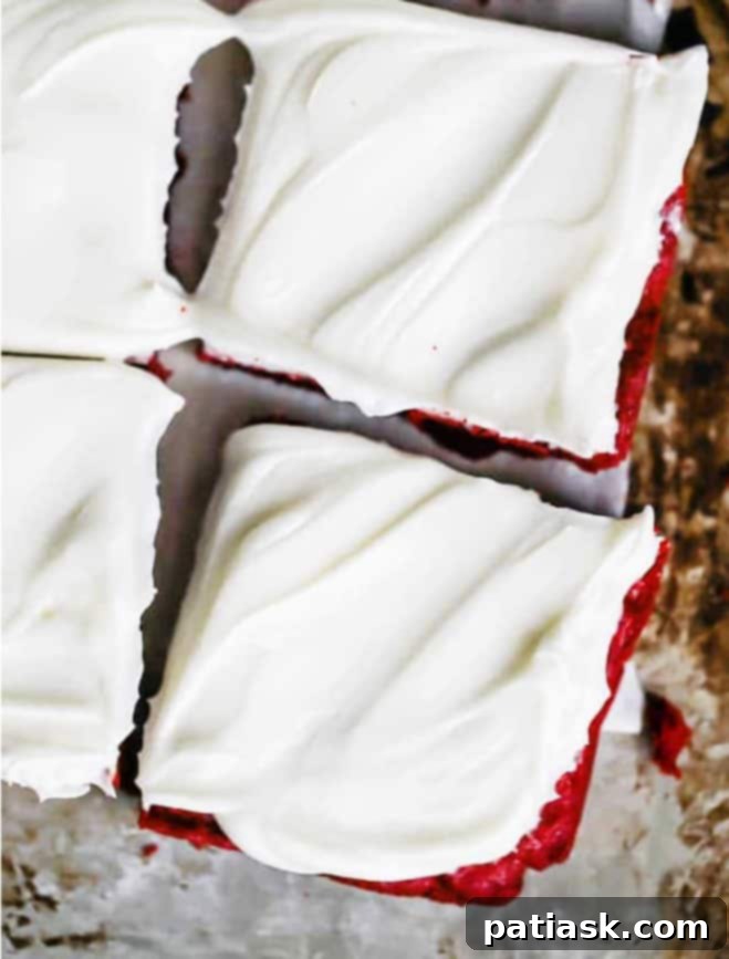 Red velvet bars with cream cheese frosting, cut into squares on a cooling rack, garnished with red and white sprinkles