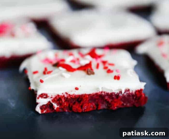 Closeup of homemade red velvet bars with thick cream cheese frosting, ready to be sliced and served