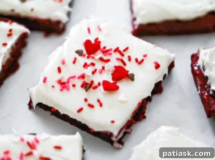 Freshly baked red velvet cookie bars cooling, topped with generous swirls of cream cheese frosting