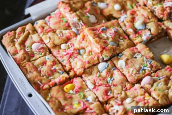Close-up of a square Cadbury Egg Cookie Bar, showcasing its chewy texture, colorful sprinkles, and mini Cadbury eggs, ready to be enjoyed