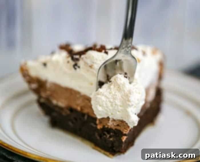 Close-up of Ultimate Triple Layer Chocolate Brownie Mousse Cream Pie, showcasing the smooth chocolate mousse and fluffy whipped cream.