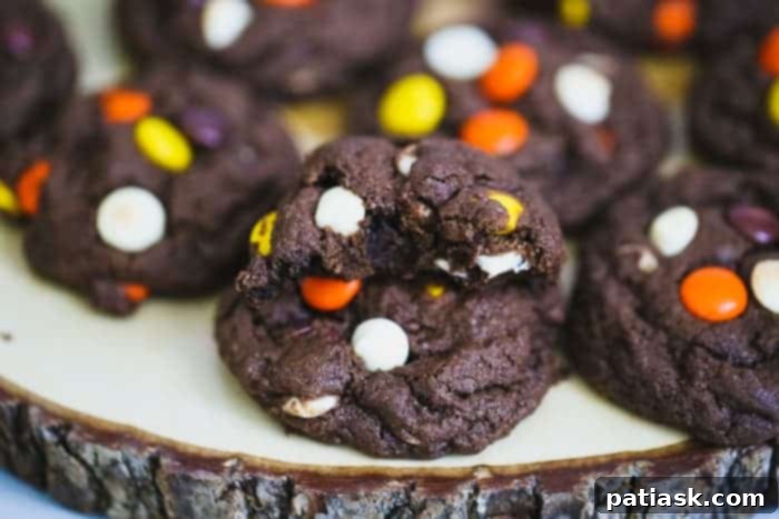 Best Fudgy Reese's Cookies Stacked Reese's Chocolate Fudge Cookies with a bite taken out, revealing the soft interior