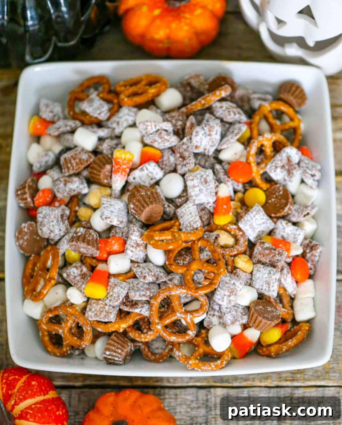 Monster Mash Puppy Chow 3 Halloween Party Puppy Chow mix recipe - close-up view of the candy, pretzels, and cereal coated in chocolate peanut butter, dusted with powdered sugar.
