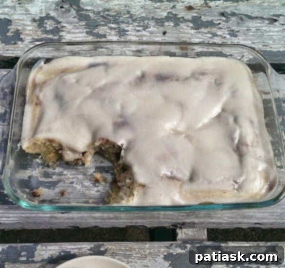 Ultimate Cinnabon Cinnamon Roll Cake 3 Close-up of a slice of Cinnabon Cinnamon Roll Cake with generous cream cheese glaze