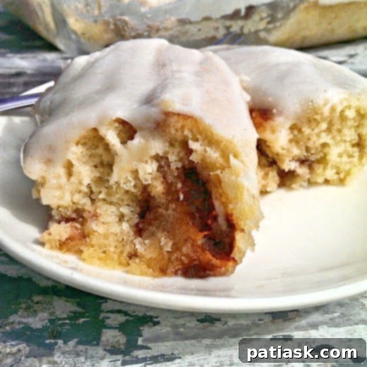 Ultimate Cinnabon Cinnamon Roll Cake 5 A large slice of Cinnabon Cinnamon Roll Cake, showing the swirl and thick glaze