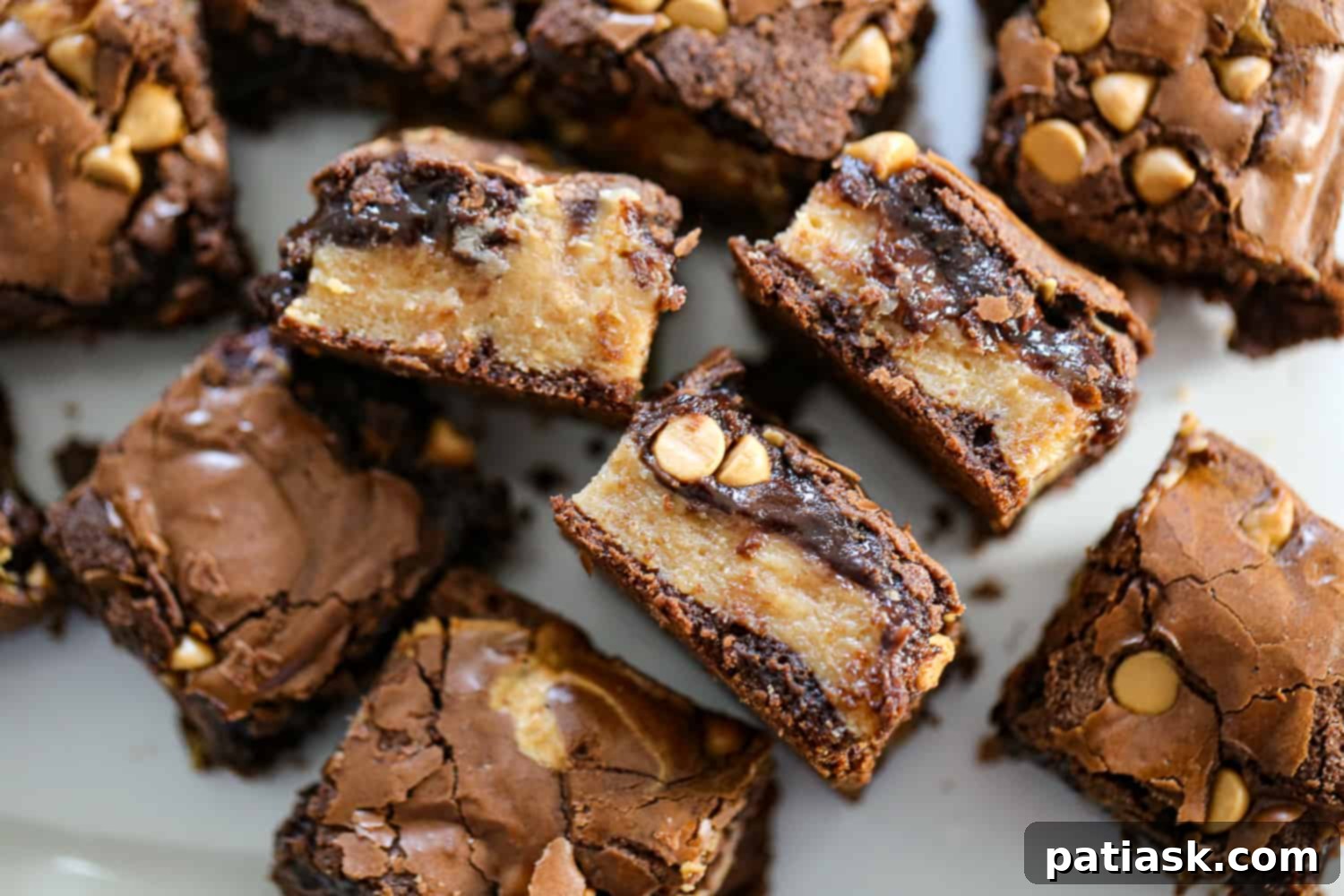 Rich and Gooey Buckeye Brownie Bars 8 Two buckeye brownie bars on a white plate, showcasing the peanut butter filling and chocolate chips